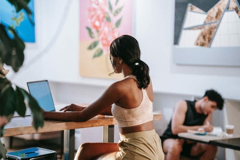 woman wearing tank top typing on laptop