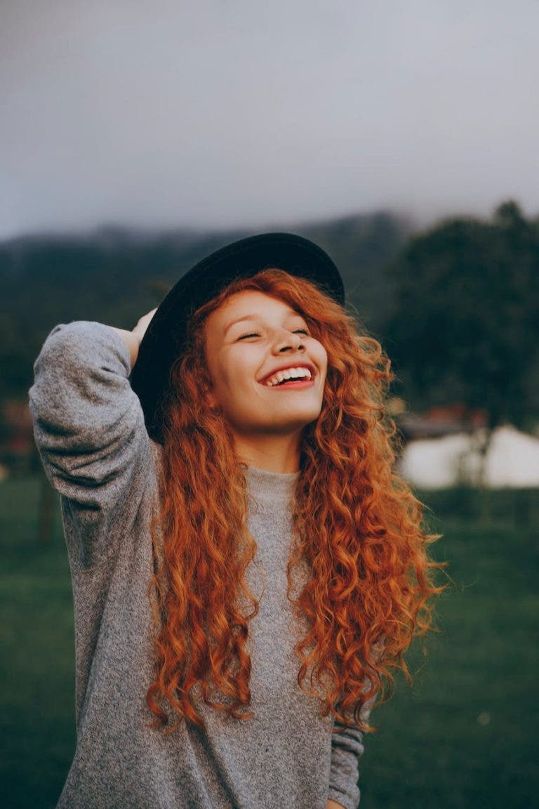 woman holding her hat while smiling