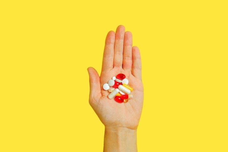 person with bunch medication pills on hand