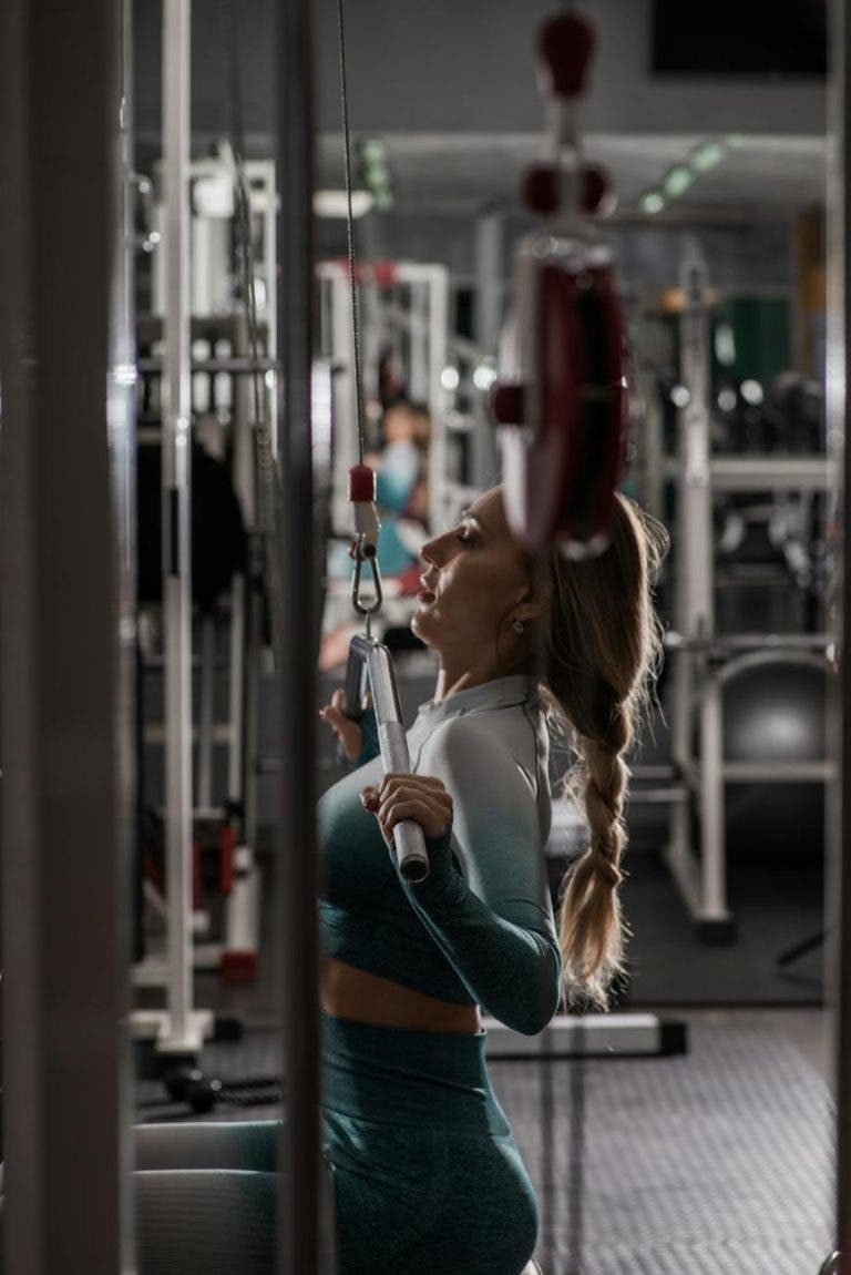 fit woman exercising on arm machine in gym